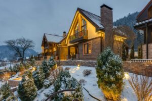 Warmly lit chalet surrounded by snow-covered trees in a picturesque winter setting.